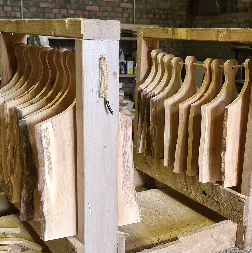 Wooden cutting boards drying on racks in a workshop.