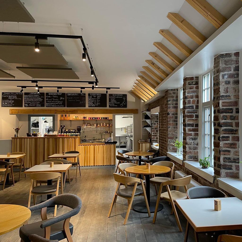 Interior of a cafe with tables and chairs, exposed brick walls, and a wooden counter.