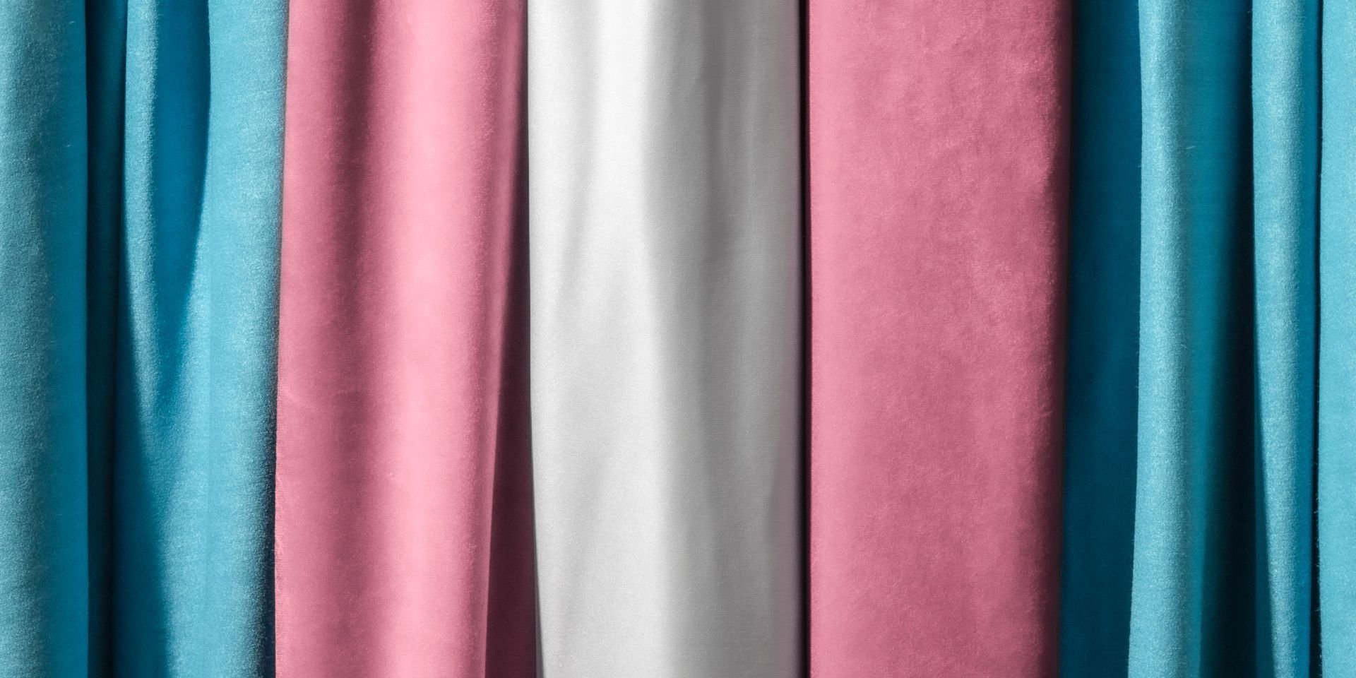 A close up of a row of pink , blue and white curtains.
