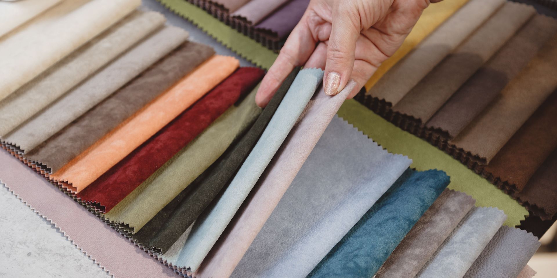 A person's hand holding fabric swatches of various colors, in a design shop.
