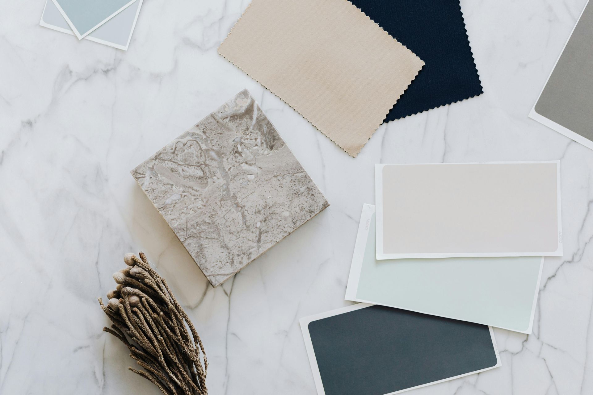 Swatches of fabric and paint colors on marble, including beige, blue, and gray.