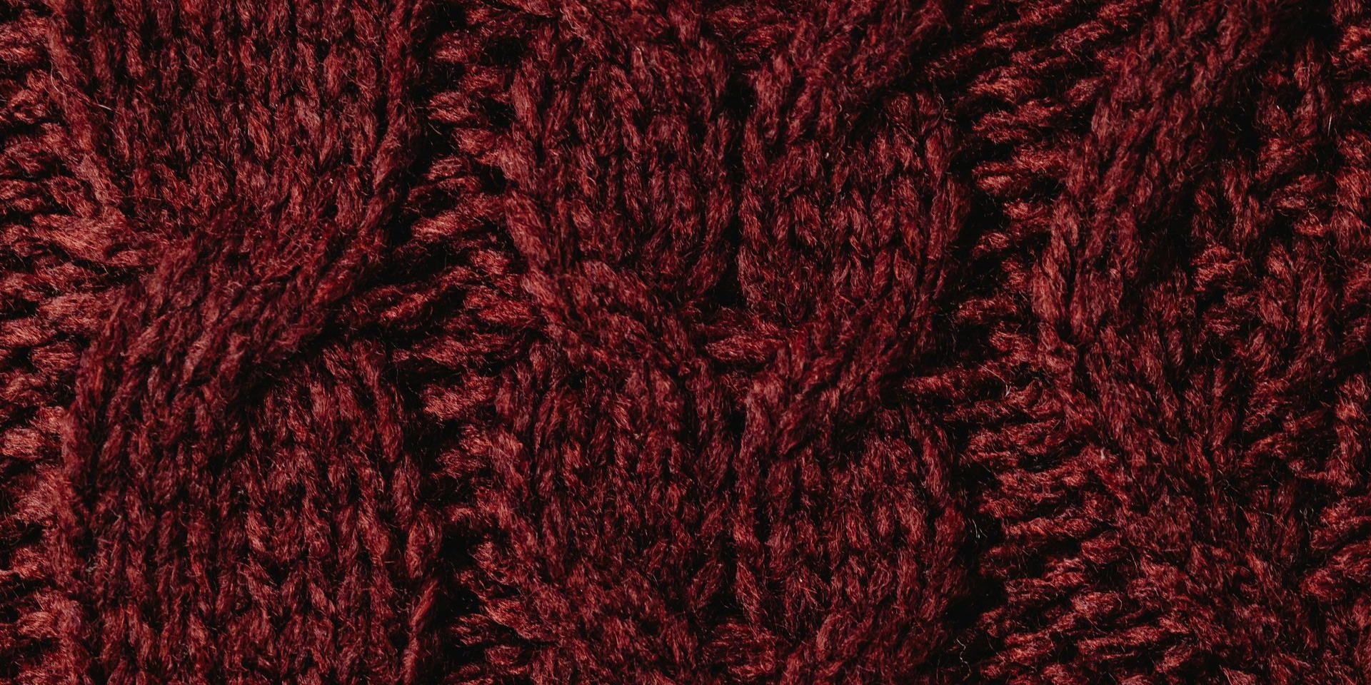 Close-up of a burgundy knitted fabric with a cable design.