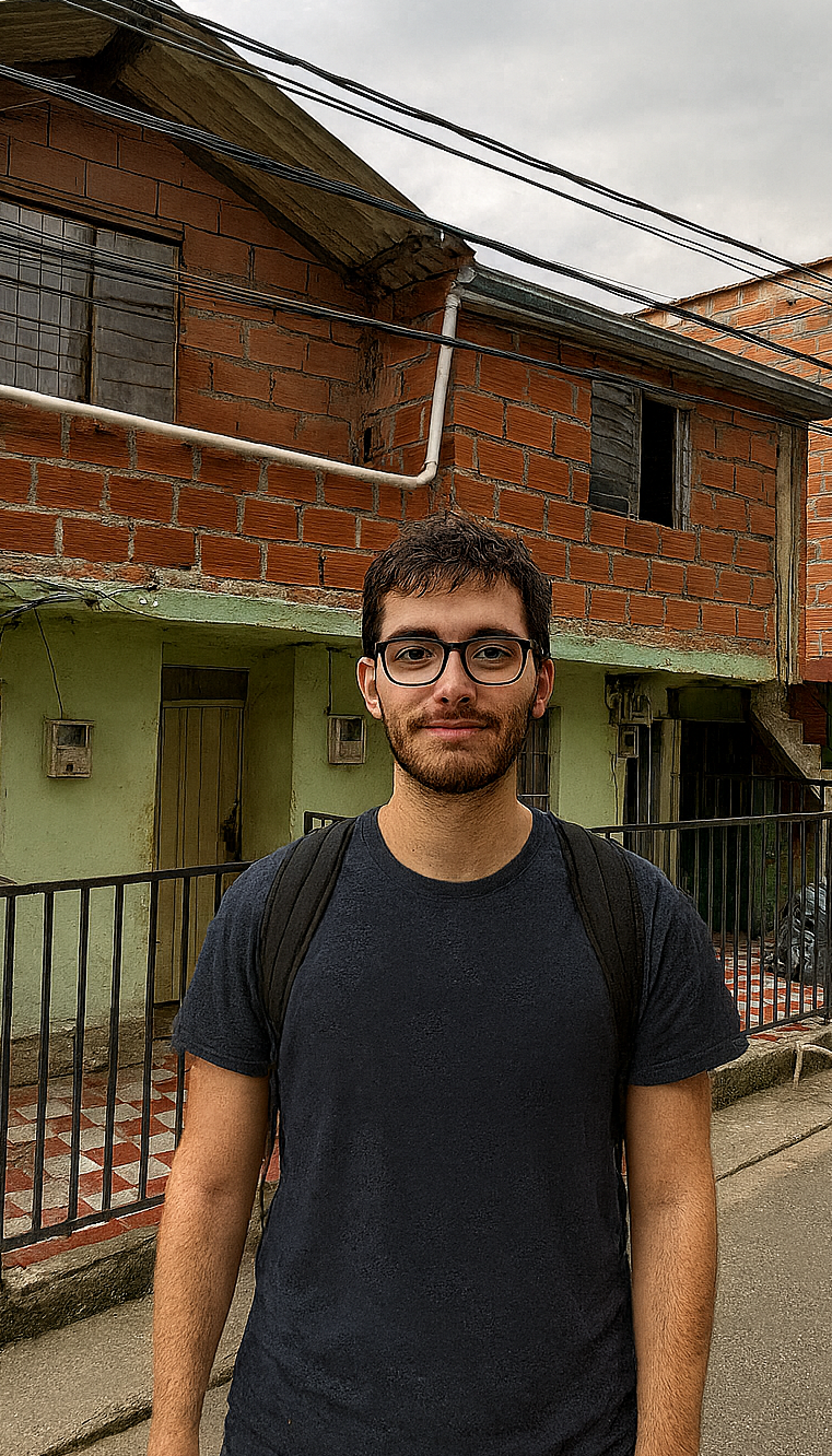 Man with glasses and backpack stands on a street in front of a brick building.