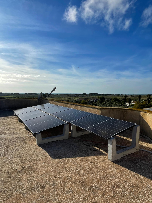 Pannelli solari su un tetto contro un cielo azzurro, che generano energia rinnovabile.