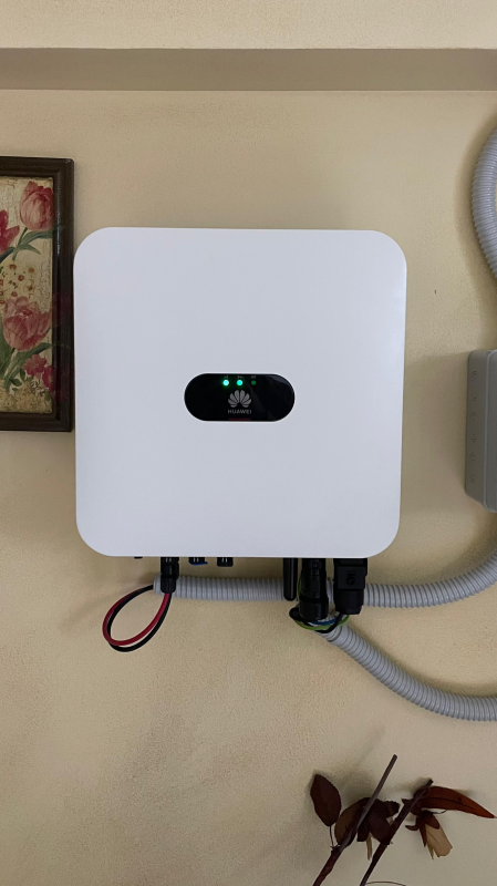 Inverter solare bianco sulla parete, luci verdi accese. Cavi collegati.