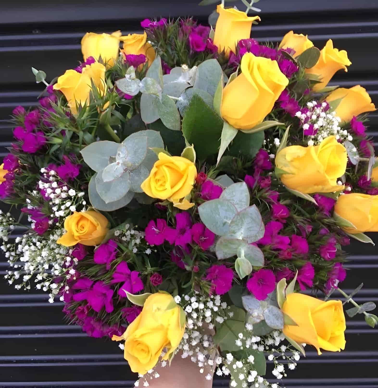 A Person Is Holding A Bouquet Of Yellow And Purple Flowers — The House of Flowers In Kirwan, QLD