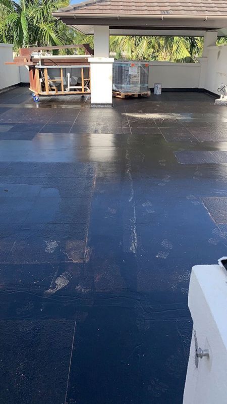 A Roof With A Ladder On It Is Being Painted Black — Eldred Waterproofing In Whitfield, QLD