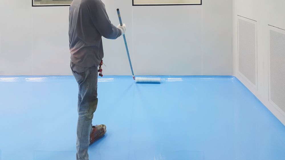 A Man Is Cleaning A Blue Floor With A Mop — Eldred Waterproofing In Whitfield, QLD