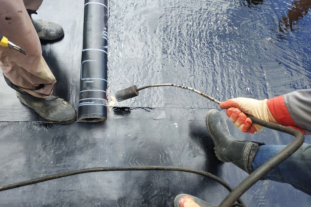 A Person Is Using A Torch On A Piece Of Roofing Material — Eldred Waterproofing In Trinity Beach, QLD