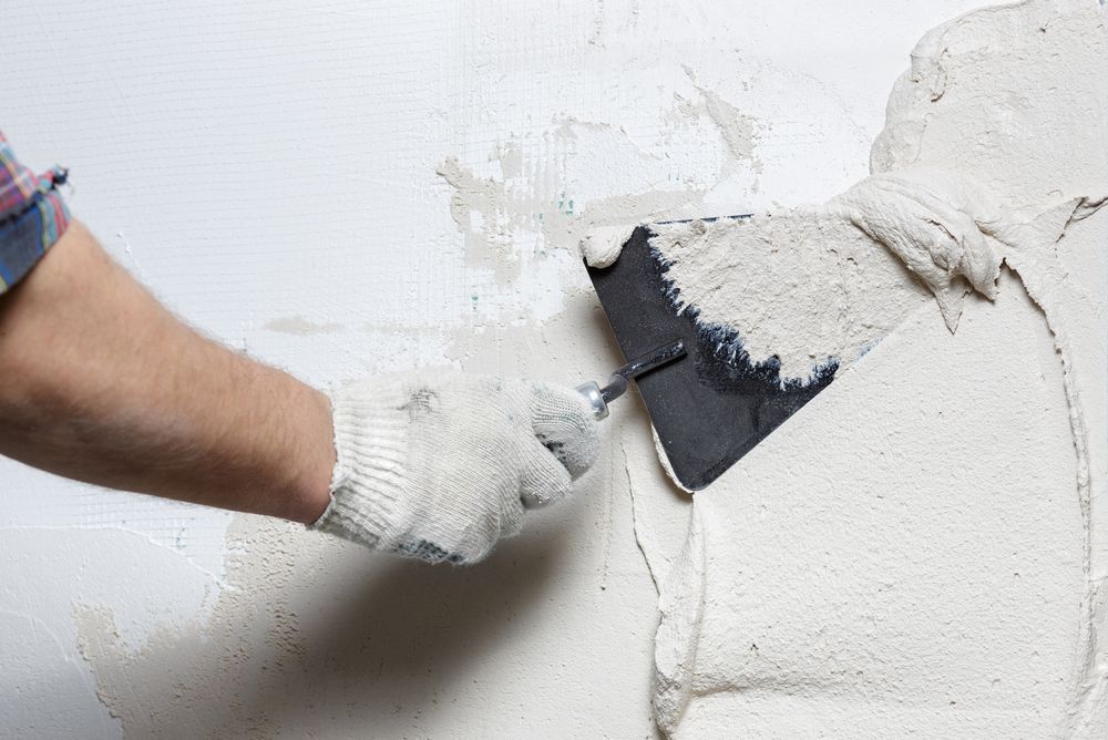 A Man Is Plastering A Wall With A Spatula — Eldred Waterproofing In Whitfield, QLD