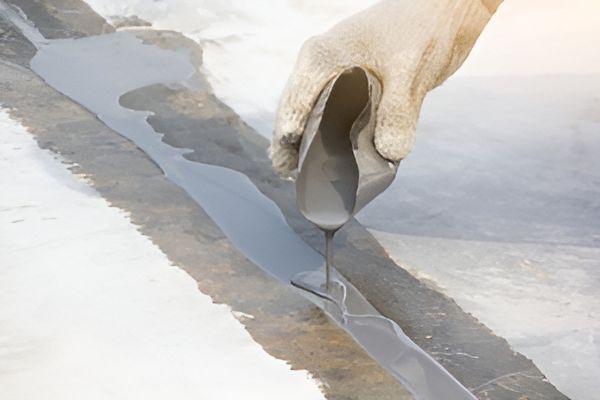 A Person Is Pouring A Liquid Into A Hole In The Ground — Eldred Waterproofing In Whitfield, QLD