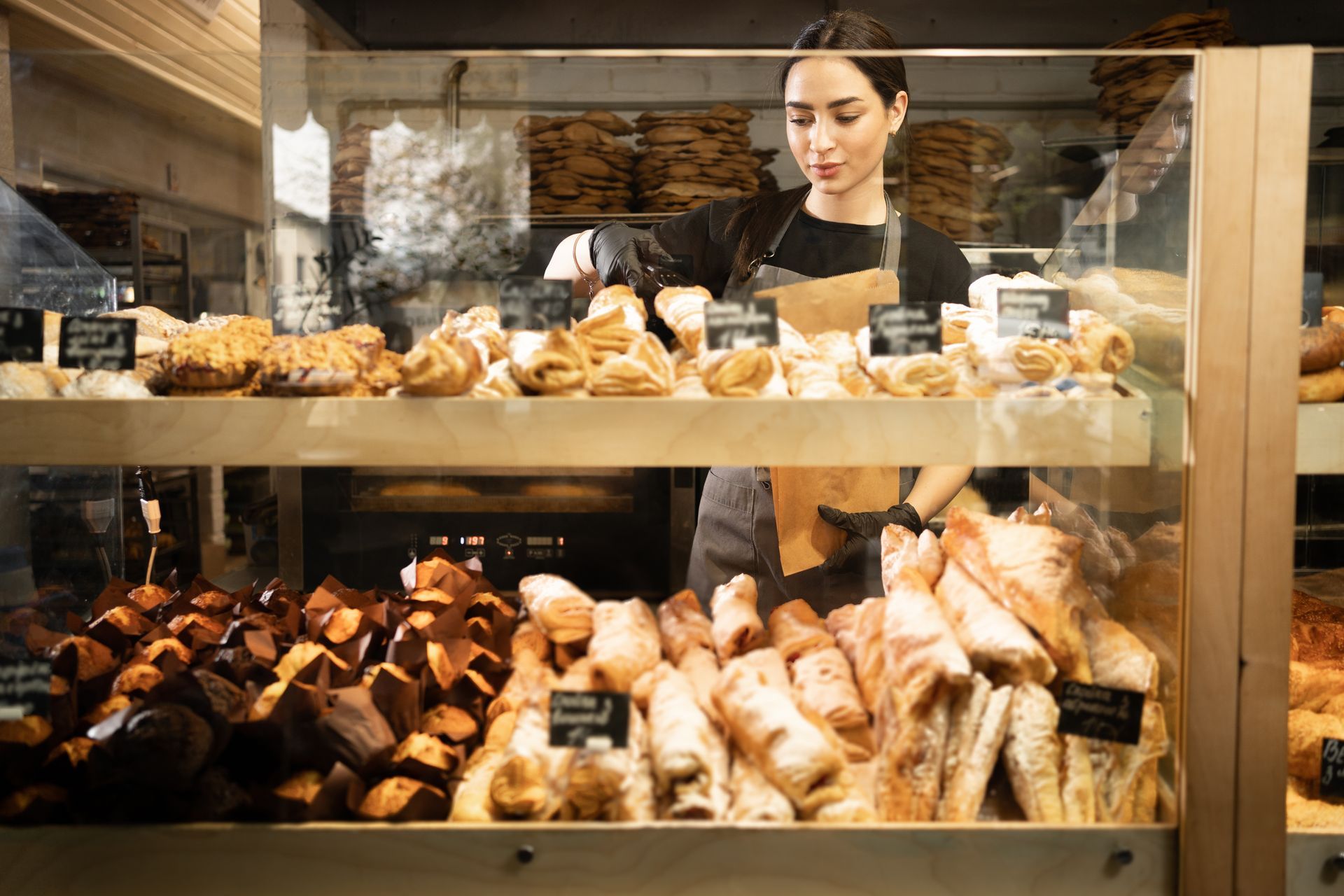 A woman stands behind the counter of a bread section in a supermarket. A woman stands behind the counter of a bread section in a supermarket.