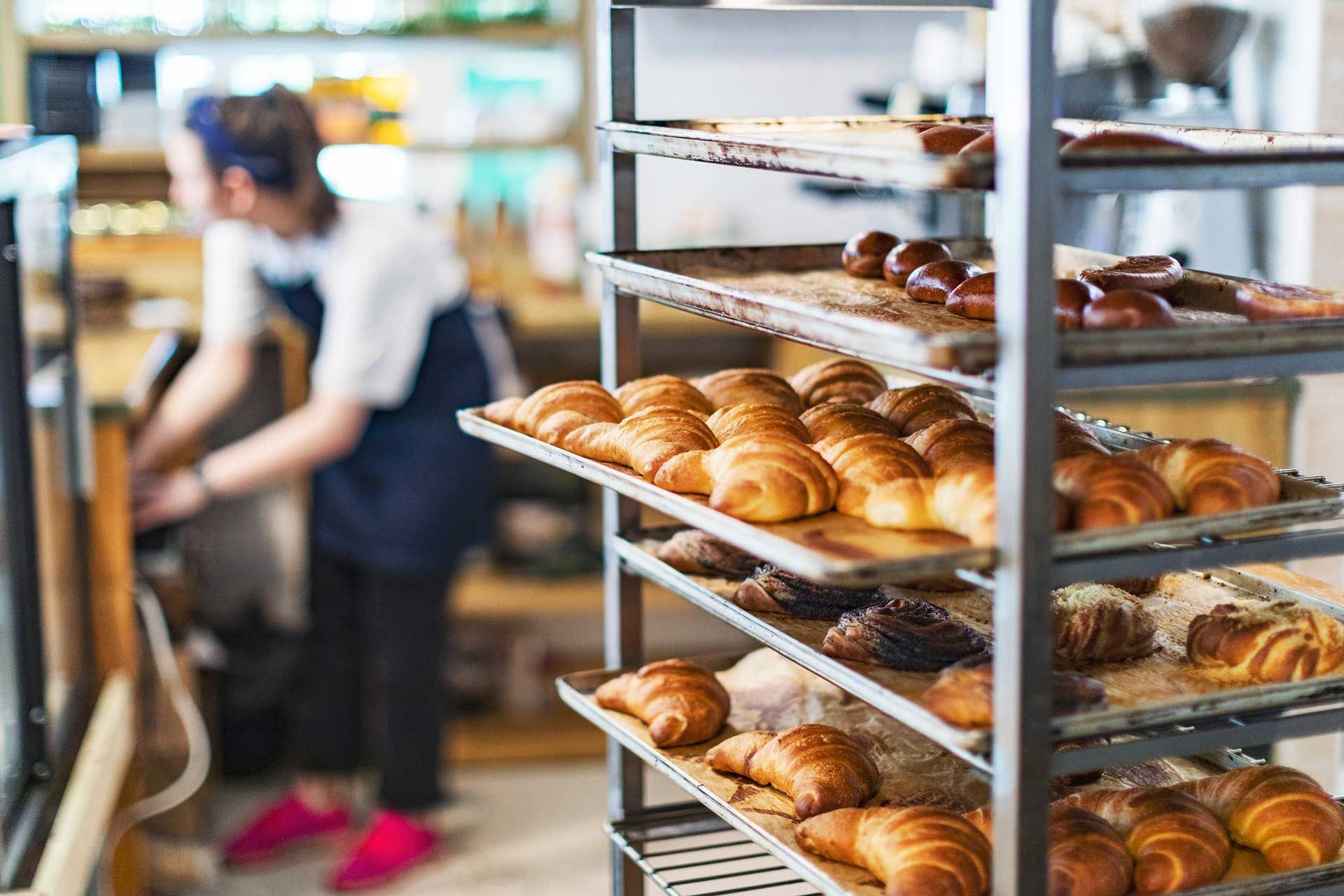 Fresh bread and croissants in a bakery in cooling rack.