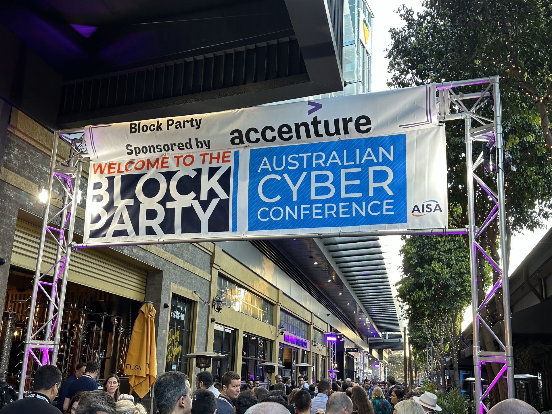 A group of people are gathered under a banner that says australian cyber conference