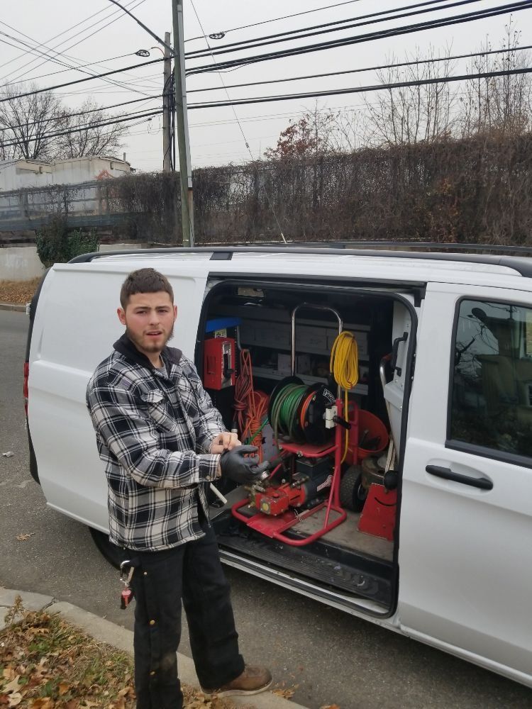 A man is standing in front of a white van with tools in the back.