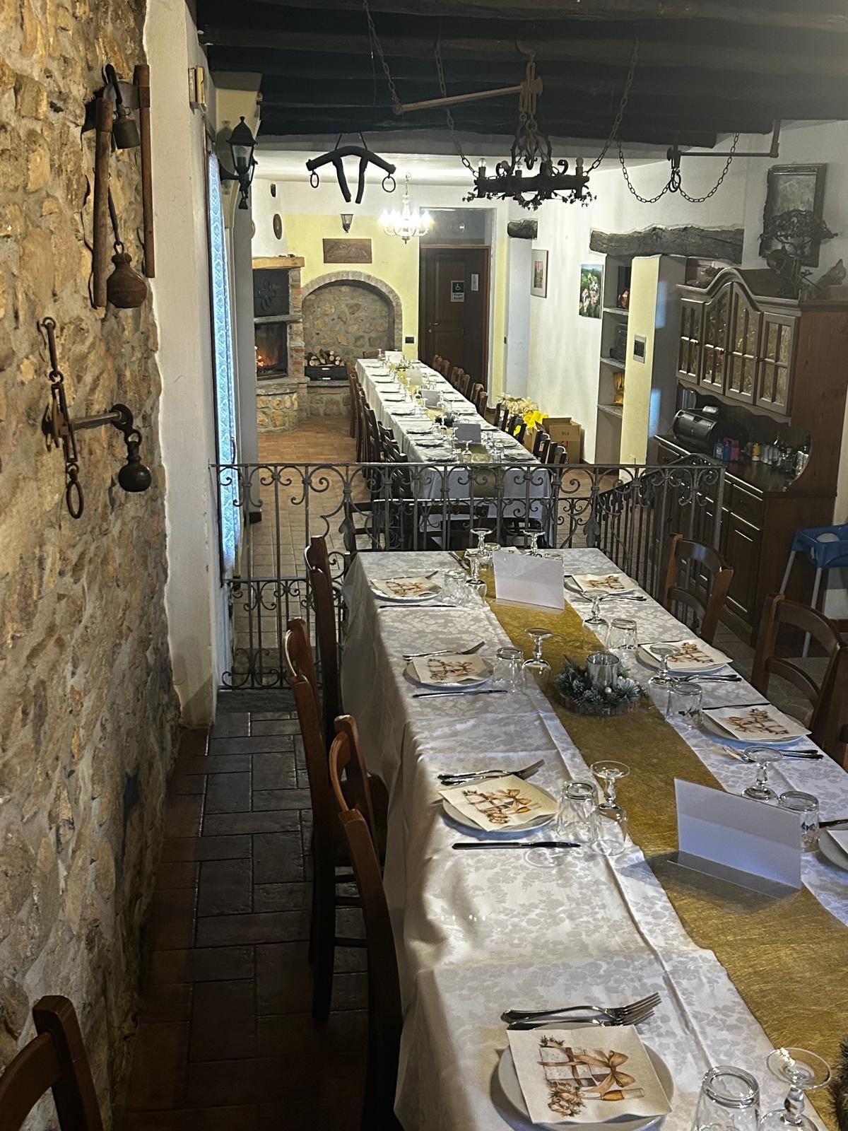 Tavoli apparecchiati per una festa in una sala da pranzo rustica con tovaglie bianche e gialle.