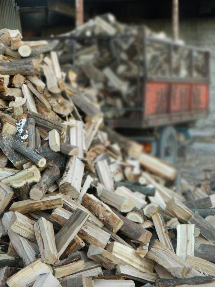 Catasta di legna da ardere accatastata, di diverse tonalità di marrone, all'aperto.