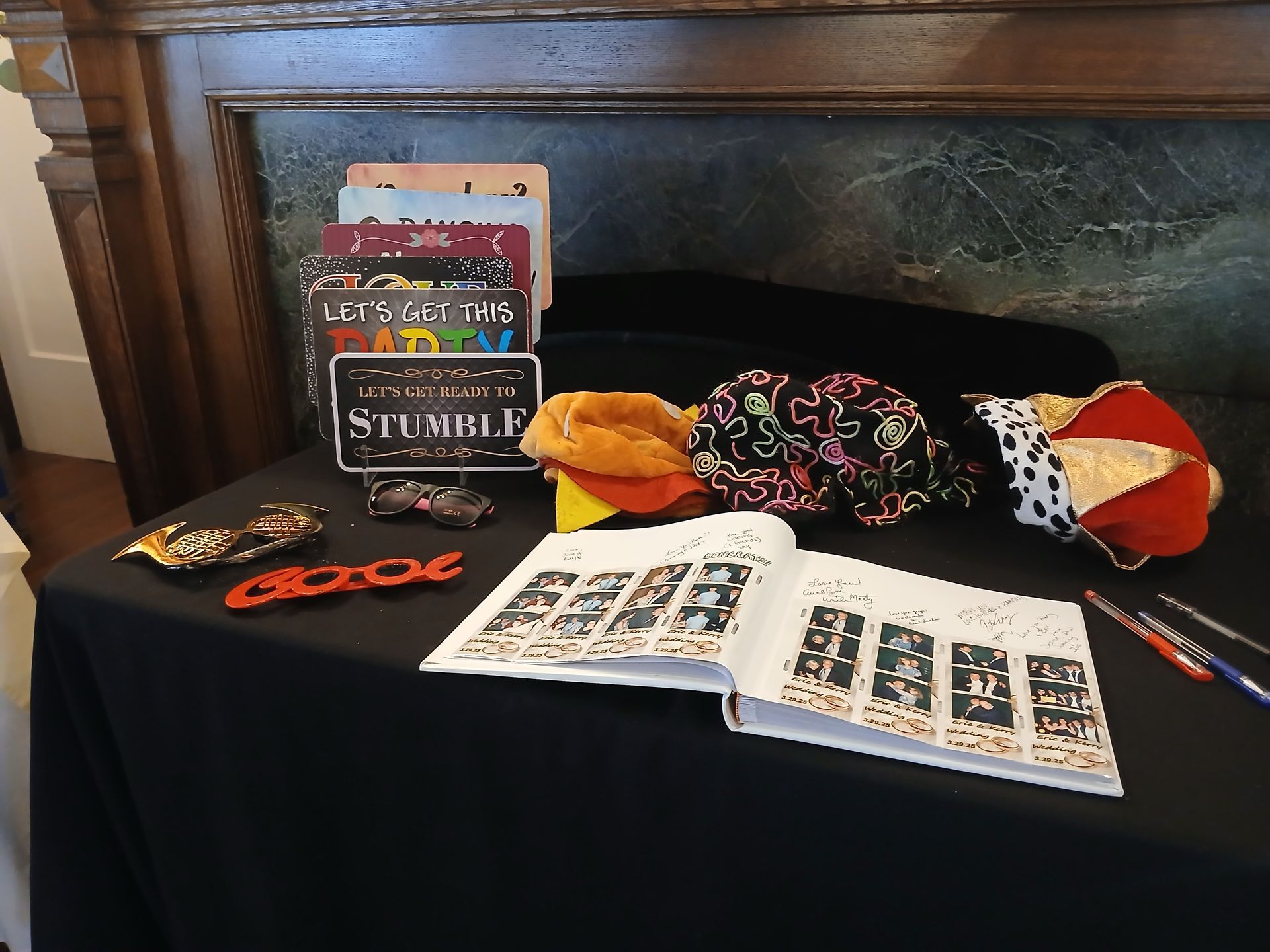 A table displays books, hats, toys, and pens against a wall.