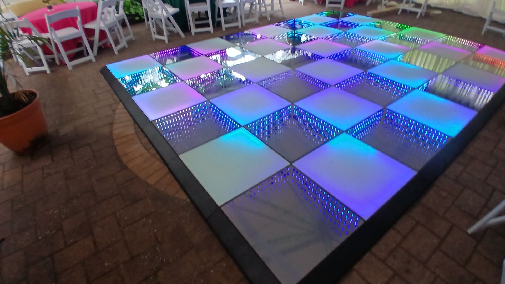 Illuminated dance floor with blue, purple, and white squares at an outdoor event.