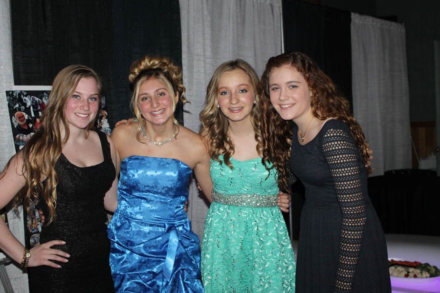Four young people in formal dresses pose together.