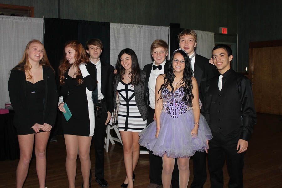 Group of teens in formal attire posing for a photo at a social event.