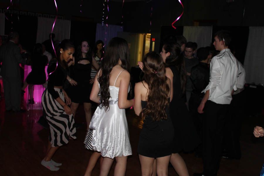 People dancing at a party, in a dimly lit room with decorations.