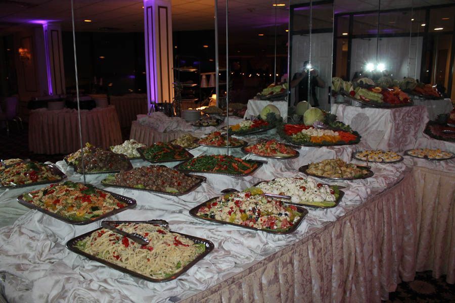 Buffet table with various salads in a brightly lit room.
