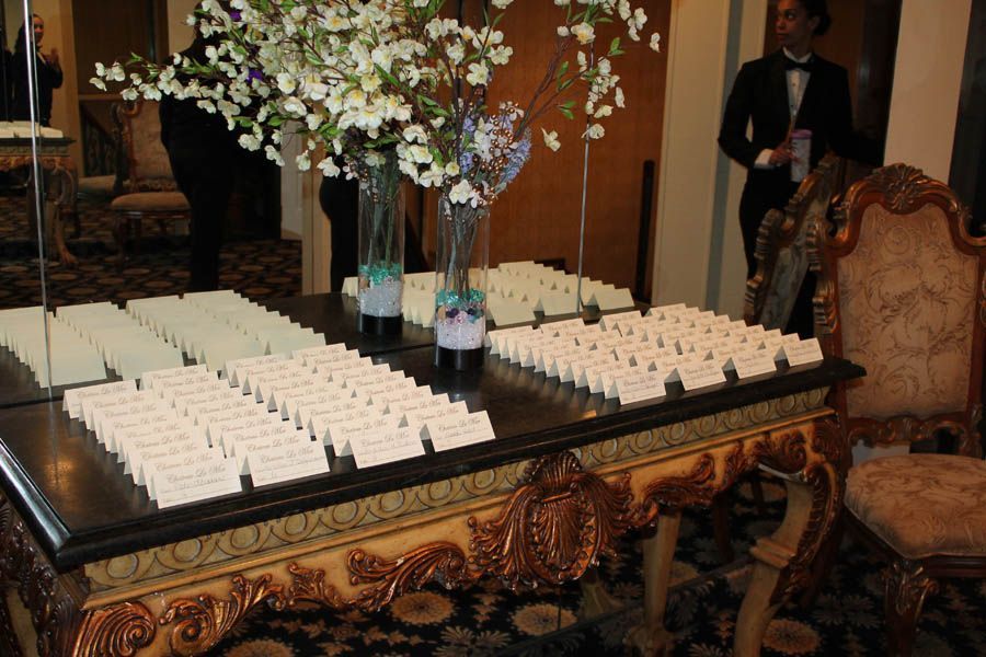 Table with guest place cards, floral arrangement, and server in a formal setting.