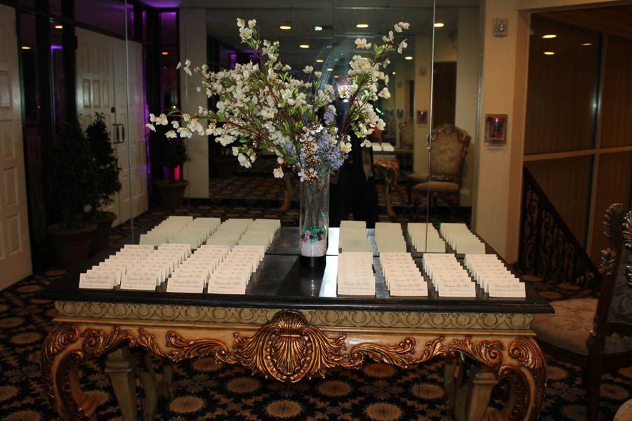 Table with place cards and floral arrangement in an ornate room.