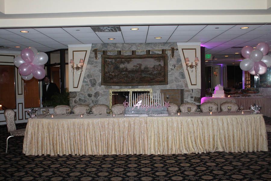 Banquet hall with decorated table and balloons in front of a stone fireplace.