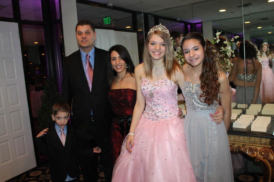 Family posing at a formal event; the young woman in the pink dress is smiling, others smiling.