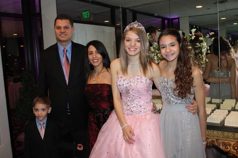 Family posing at a formal event, includes two girls in gowns, one wearing a tiara.