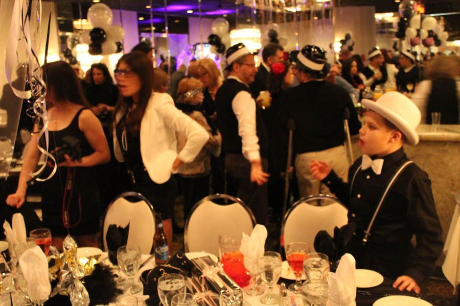 Party scene, guests in black and white attire, seated at decorated tables, socializing.