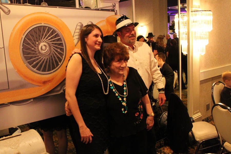 Three people pose for photo at event, standing in front of large car graphic.