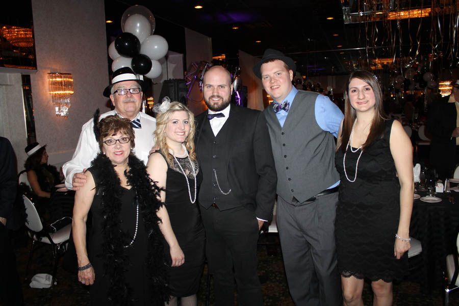 Group of people dressed in 1920s attire at a party, black and white color scheme.