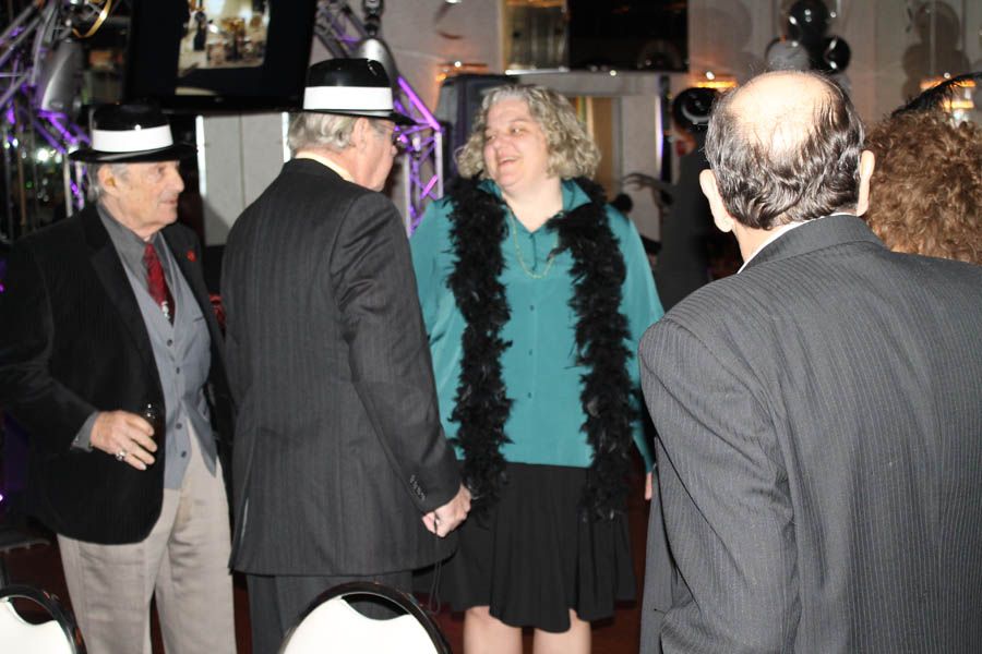 Group of people at a party, some wearing hats and a boa.