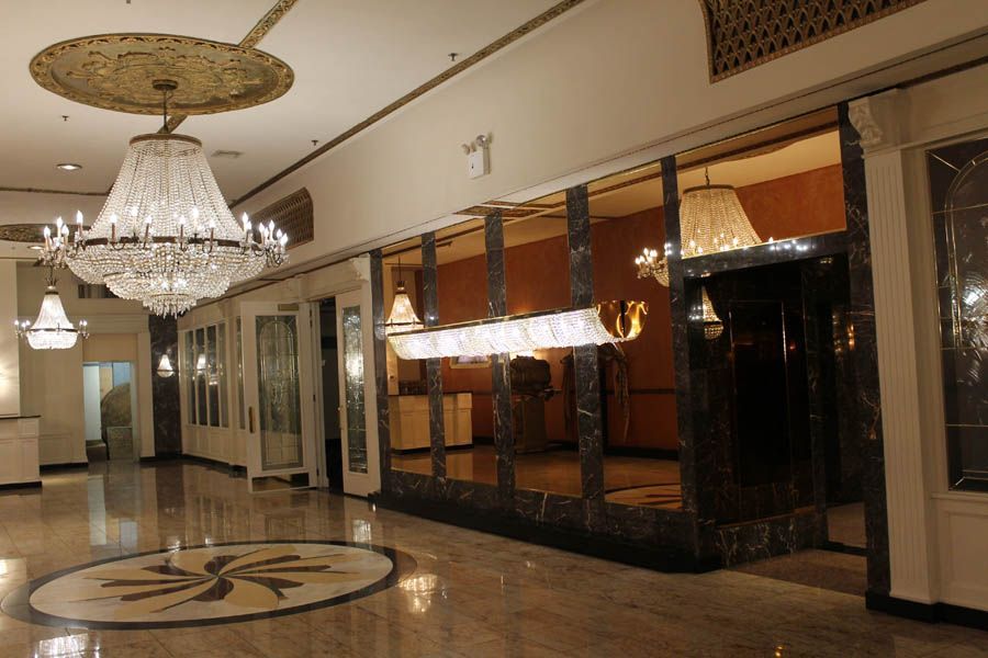 Elegant hotel lobby with marble floors, crystal chandeliers, and mirrored walls.
