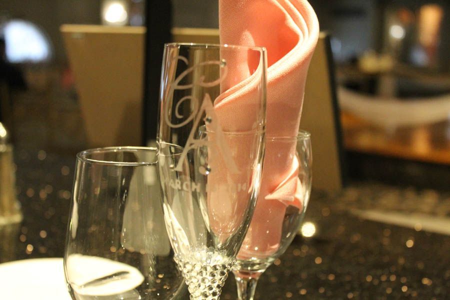 Champagne flutes and a water glass on a table with a pink napkin, elegant setting.