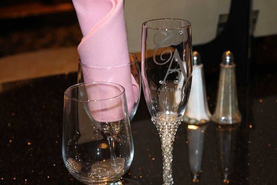 Champagne flutes and wine glass on a dark surface, one etched with an 