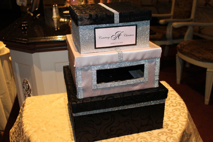 Stacked decorative gift boxes in black, pink, and silver with a slit opening.