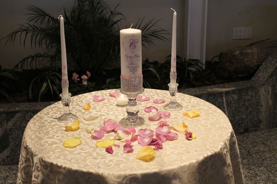 Wedding ceremony table with lit candles, rose petals.