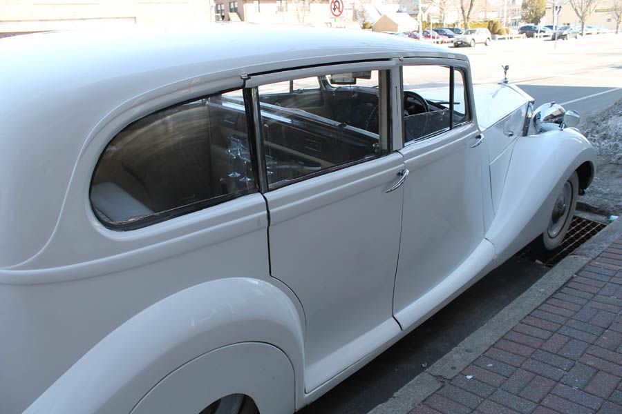 White classic car parked on a city street, partially in view.
