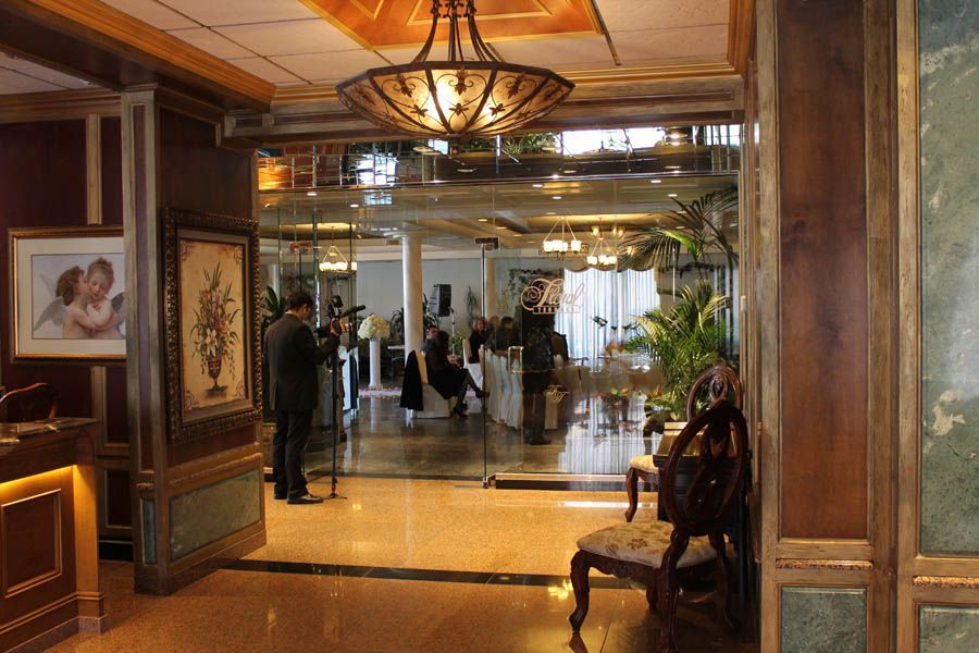 Hotel lobby entrance with glass doors, chandelier, and a person filming with a camera.
