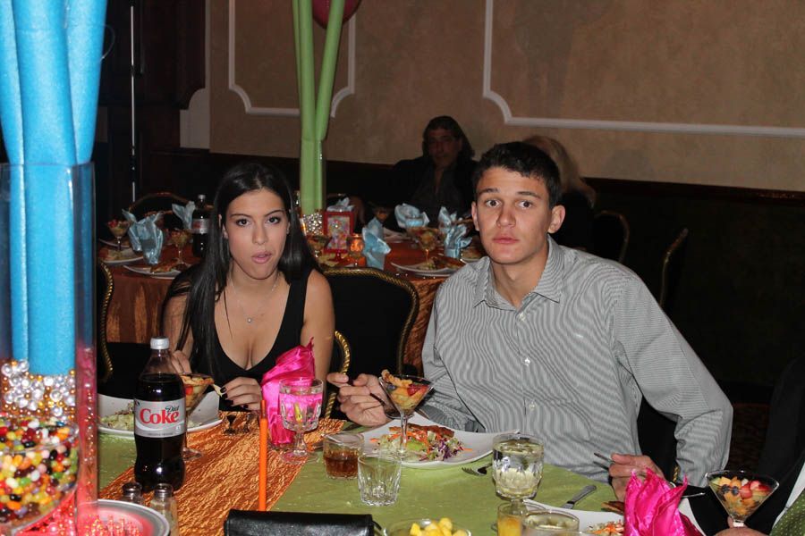 Woman and man at a table with food, drinks, and party decorations. The woman has an expression of surprise.