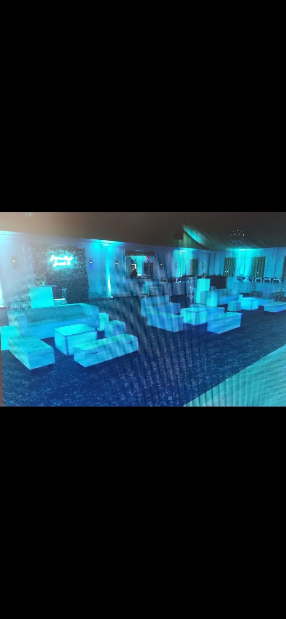 Blue-lit lounge or club interior with seating arrangements, pillars and ambient lighting.