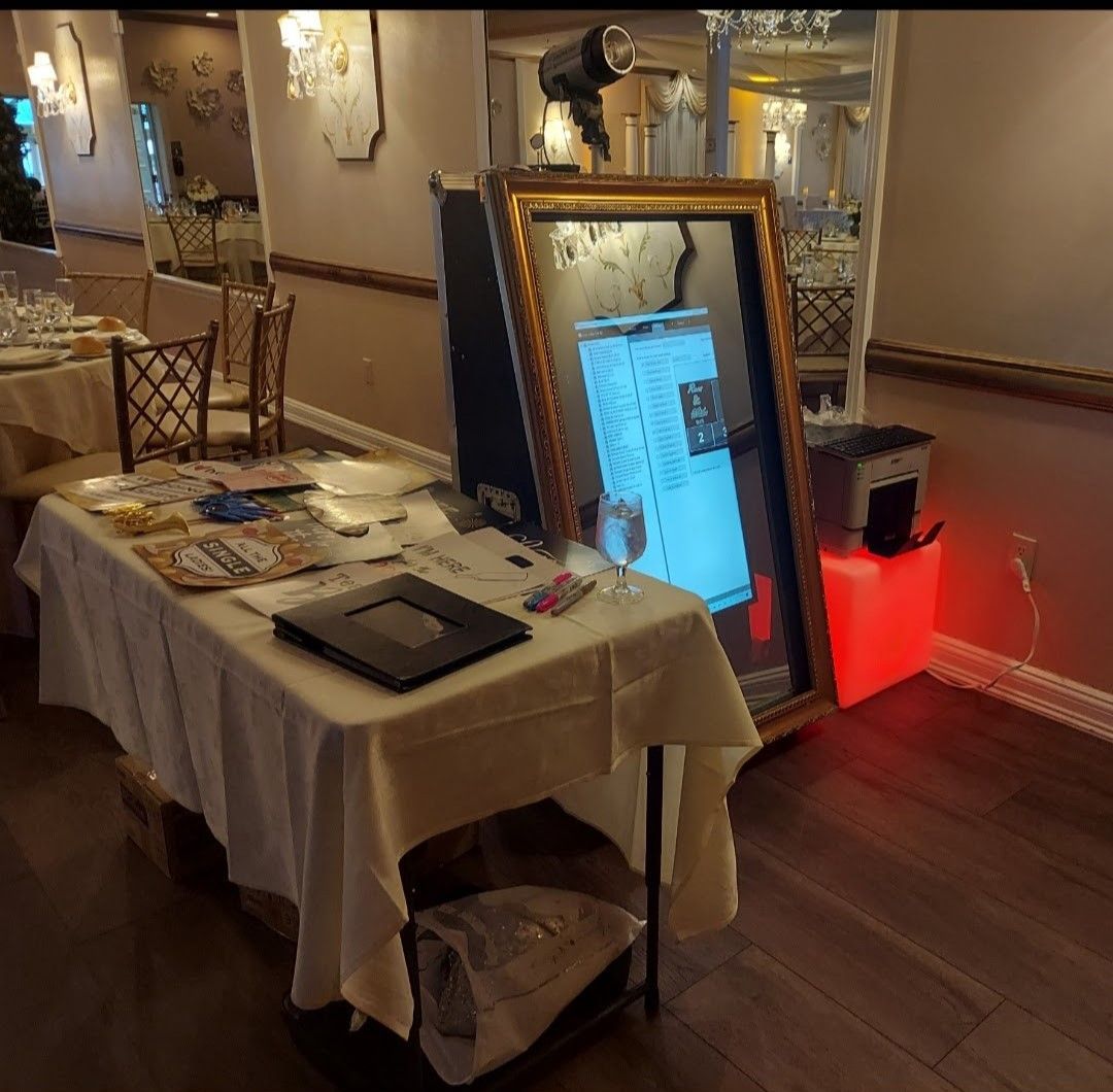 Photo booth with mirror, table with brochures and supplies, set in a restaurant with gold accents.