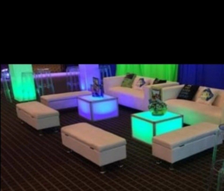White illuminated furniture in a room with white couches, ottomans, and coffee tables.