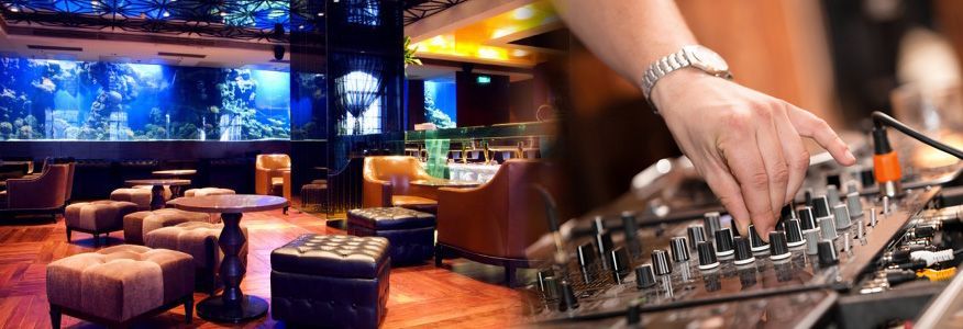 A DJ mixing music at a club with an aquarium.