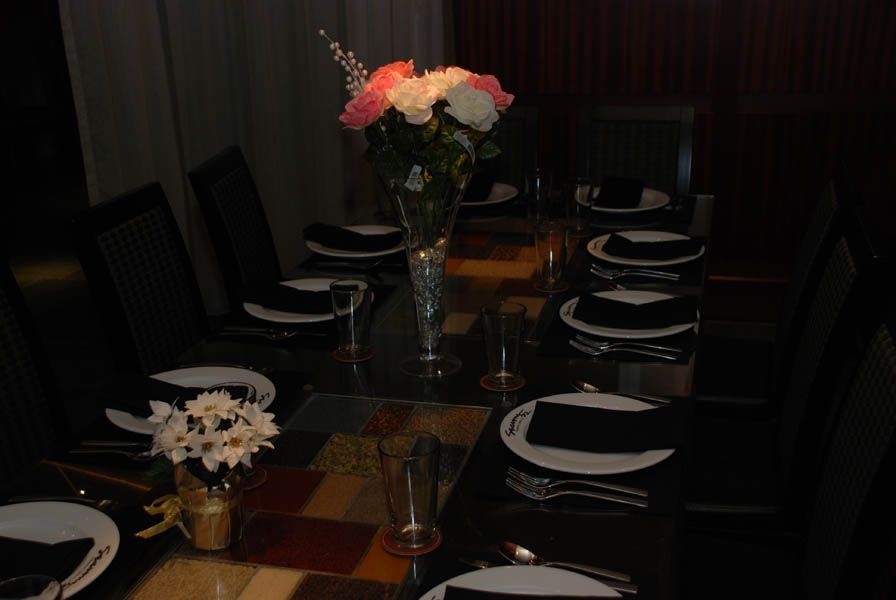 Formal dining table set for guests with flowers in center.