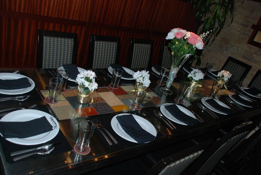 A long dining table set for a meal with plates, glasses, and flowers in a restaurant setting.